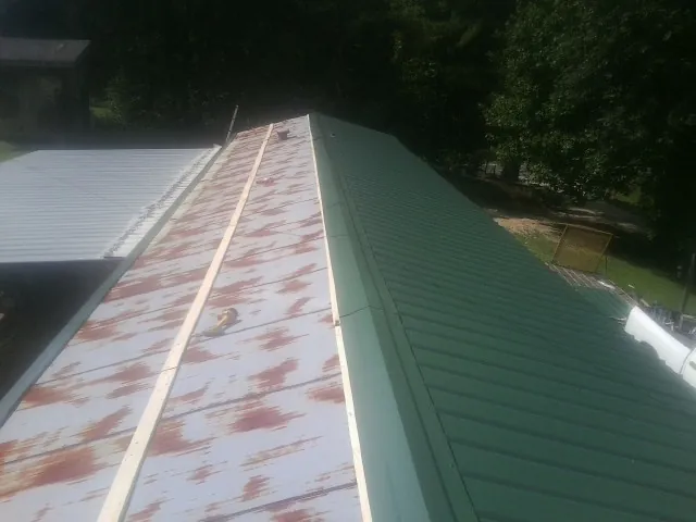 Old rusted panels beside newly installed green metal roofing — Wind Damage Roof Repair by Roofing Brothers in Catawba