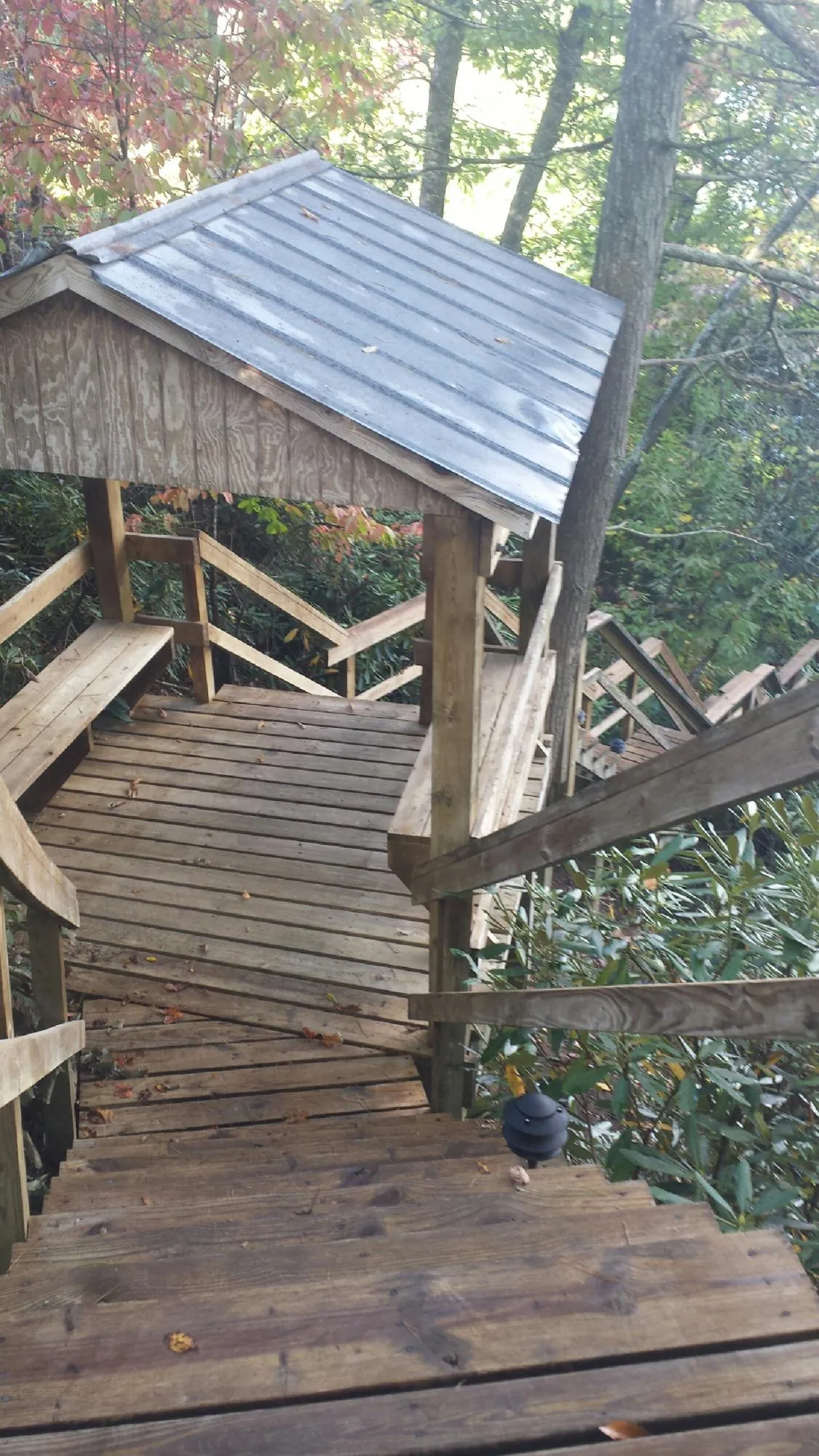 Metal roofed shelter over wooden steps on a wooded walkway — Skylight Repair & Installation work by our crew in Catawba
