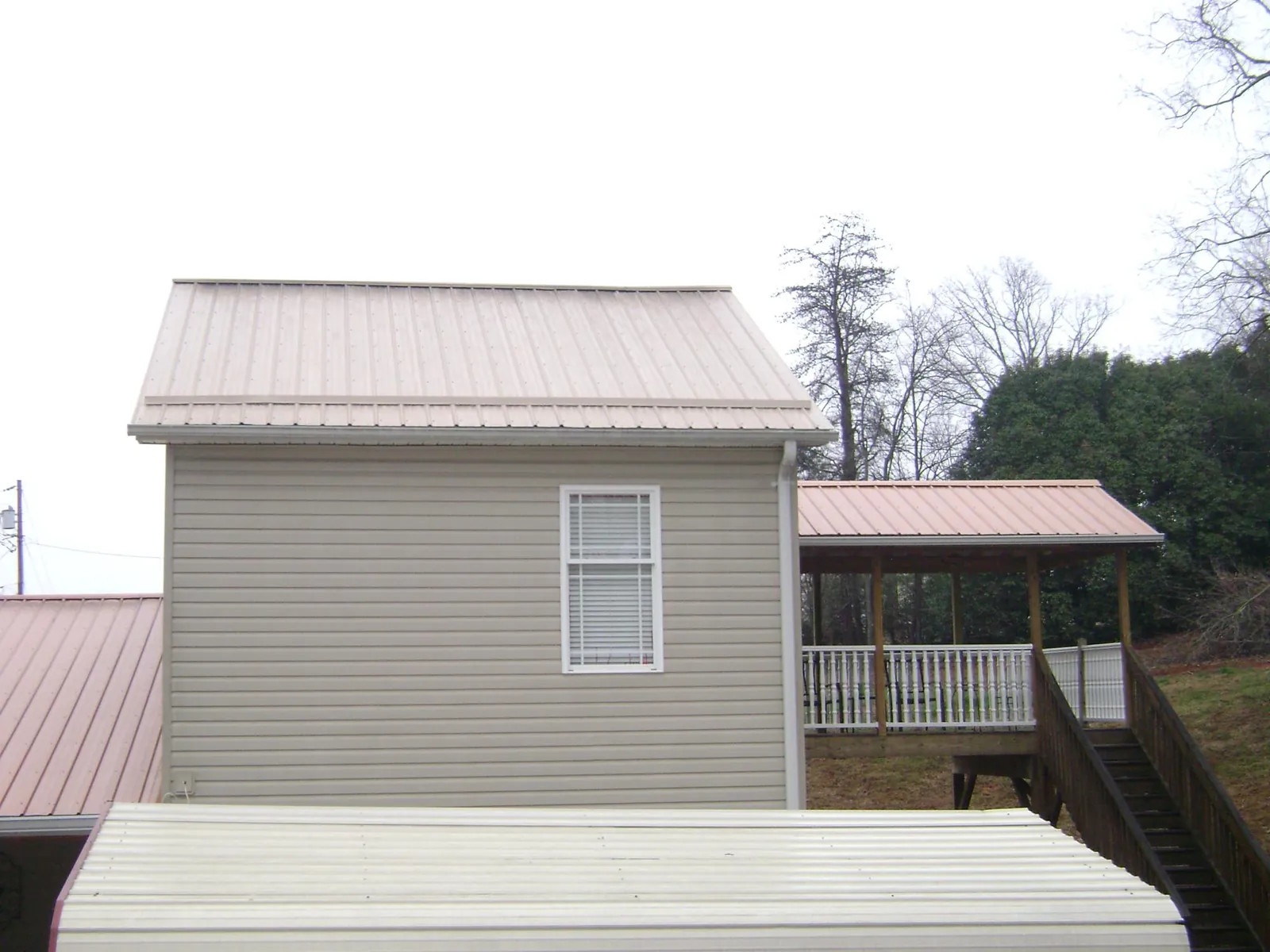 Tan metal roofs on a two story addition and attached porch, from a Roof Replacement job in Catawba