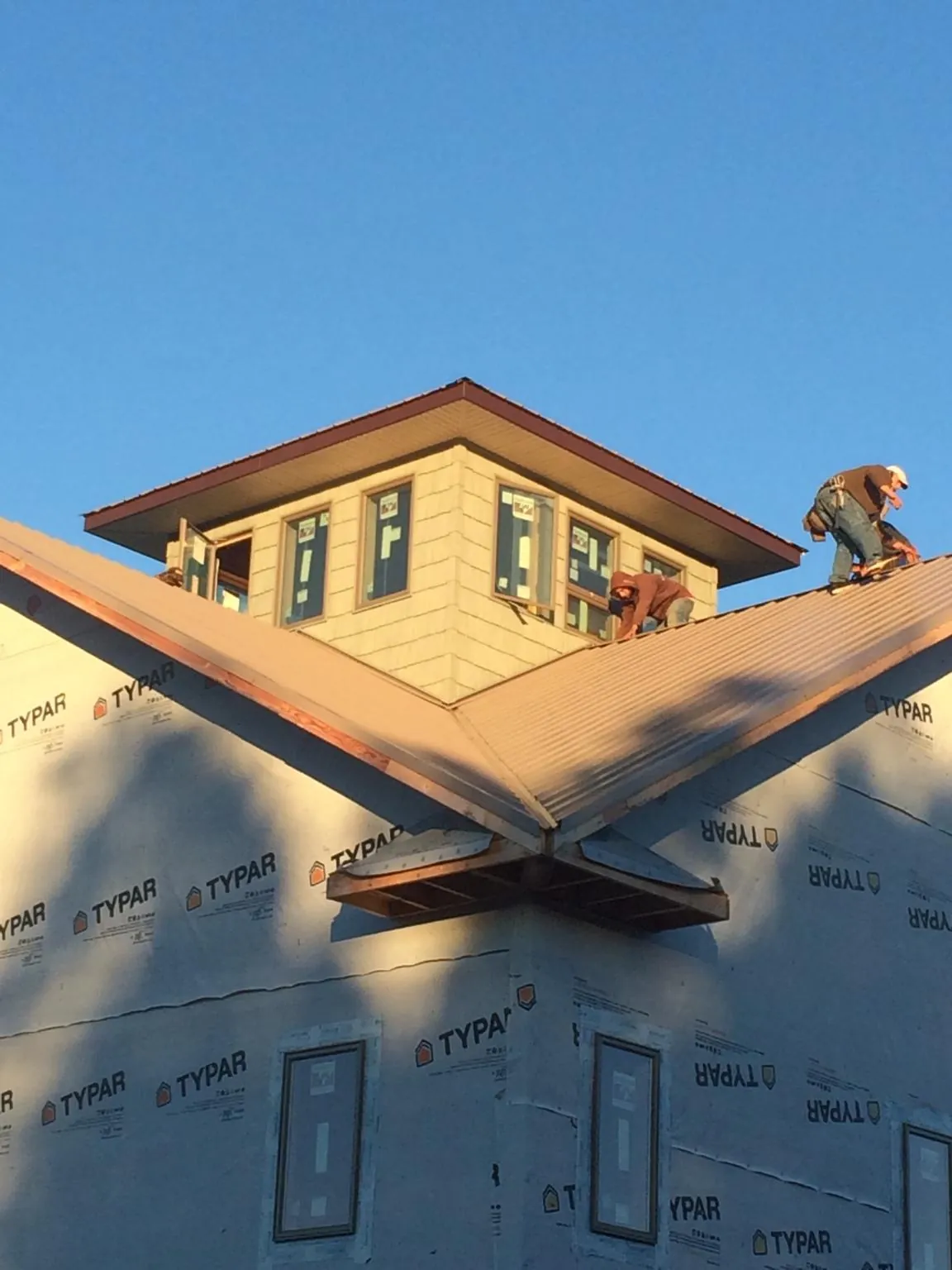 Roofers working around a rooftop cupola on a new metal roof at sunset — Roof Waterproofing in Catawba by Roofing Brothers